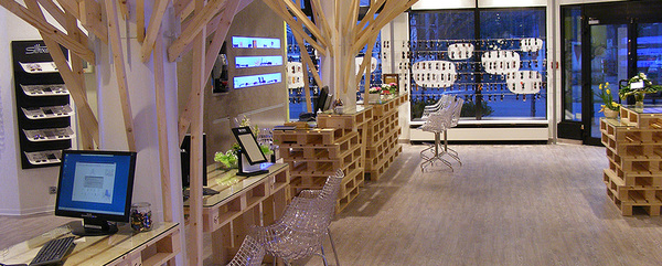 Moderner Optikerladen mit Holzdekor, Verkaufsflächen, Brillenregalen und Computerarbeitsplätzen.